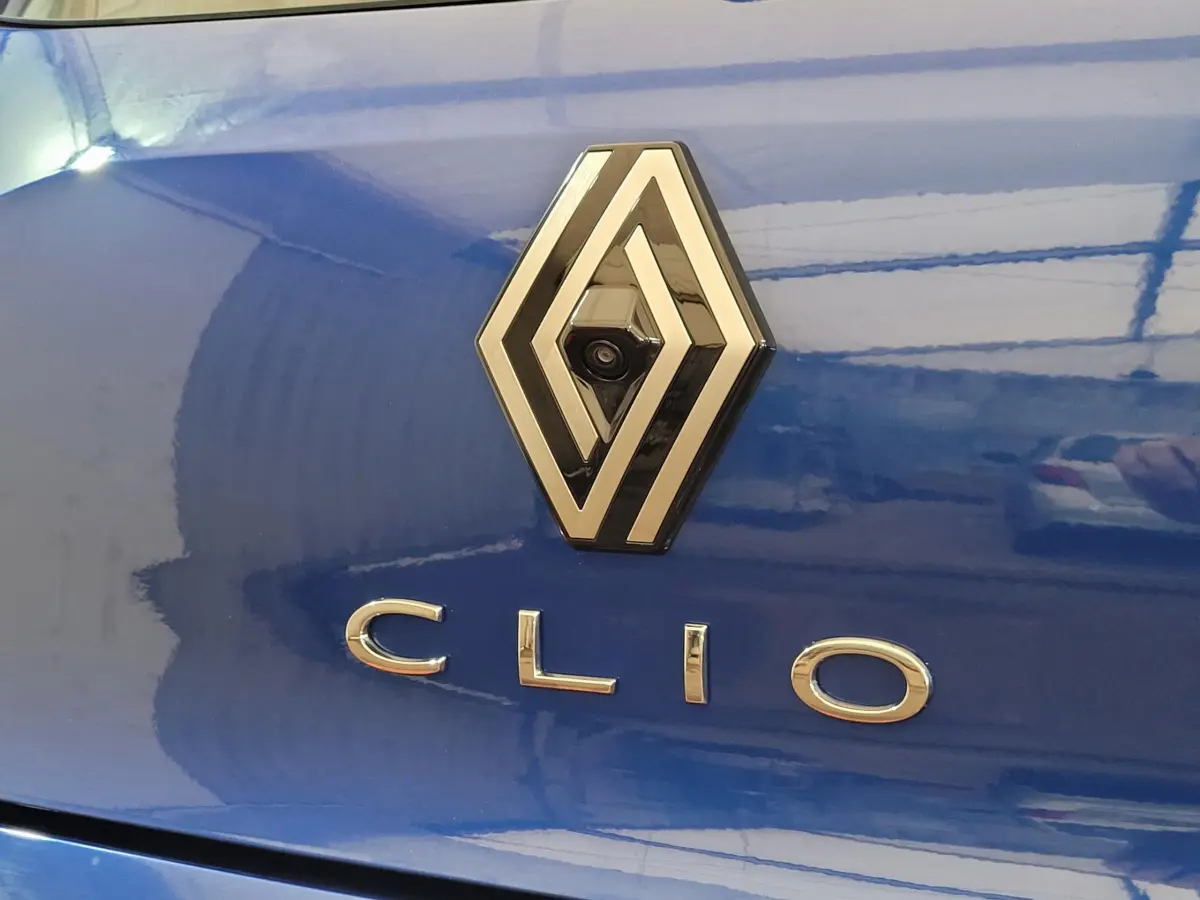 Gros plan sur le logo Renault et le nom Clio sur la malle arrière bleu vif d'une Clio Evolution 2025.