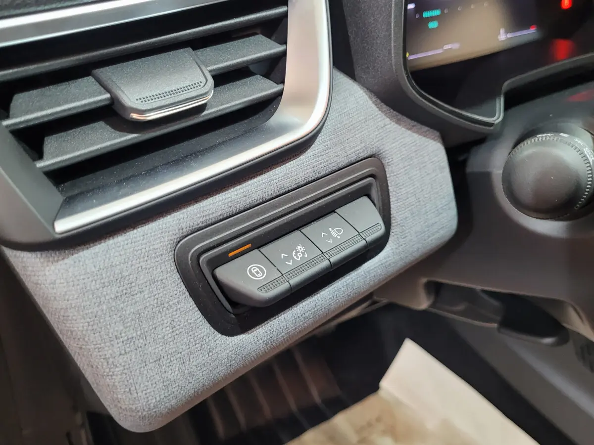Gros plan sur les commandes d'éclairage et verrouillage à gauche du tableau de bord intérieur de la Renault Clio bleu 2025.
