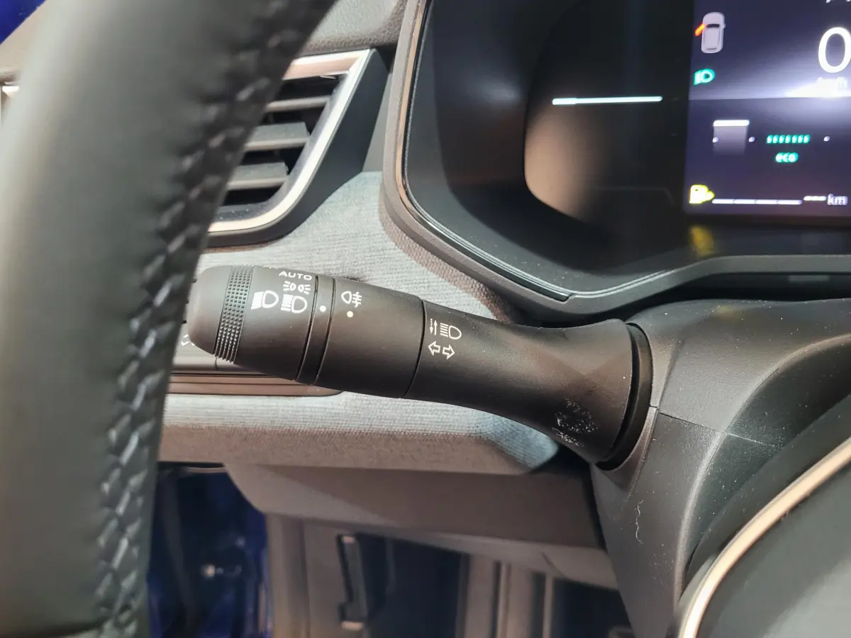 Gros plan sur la commande des phares et clignotants côté gauche du tableau de bord d'une Renault Clio bleu 2025.