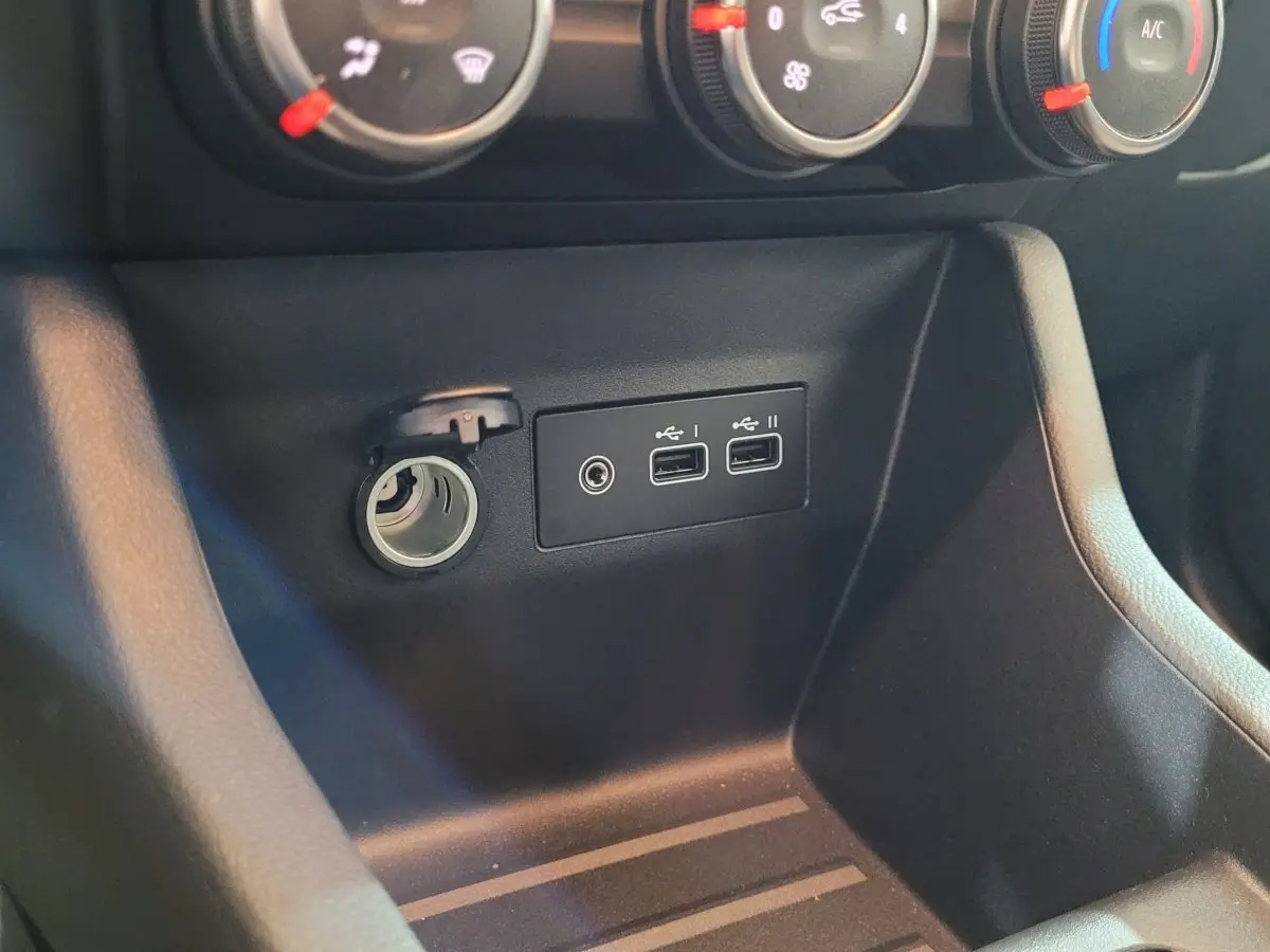 Gros plan sur la console centrale noire de la Renault Clio Evolution Blue dCi 100, montrant prises USB et allume-cigare.