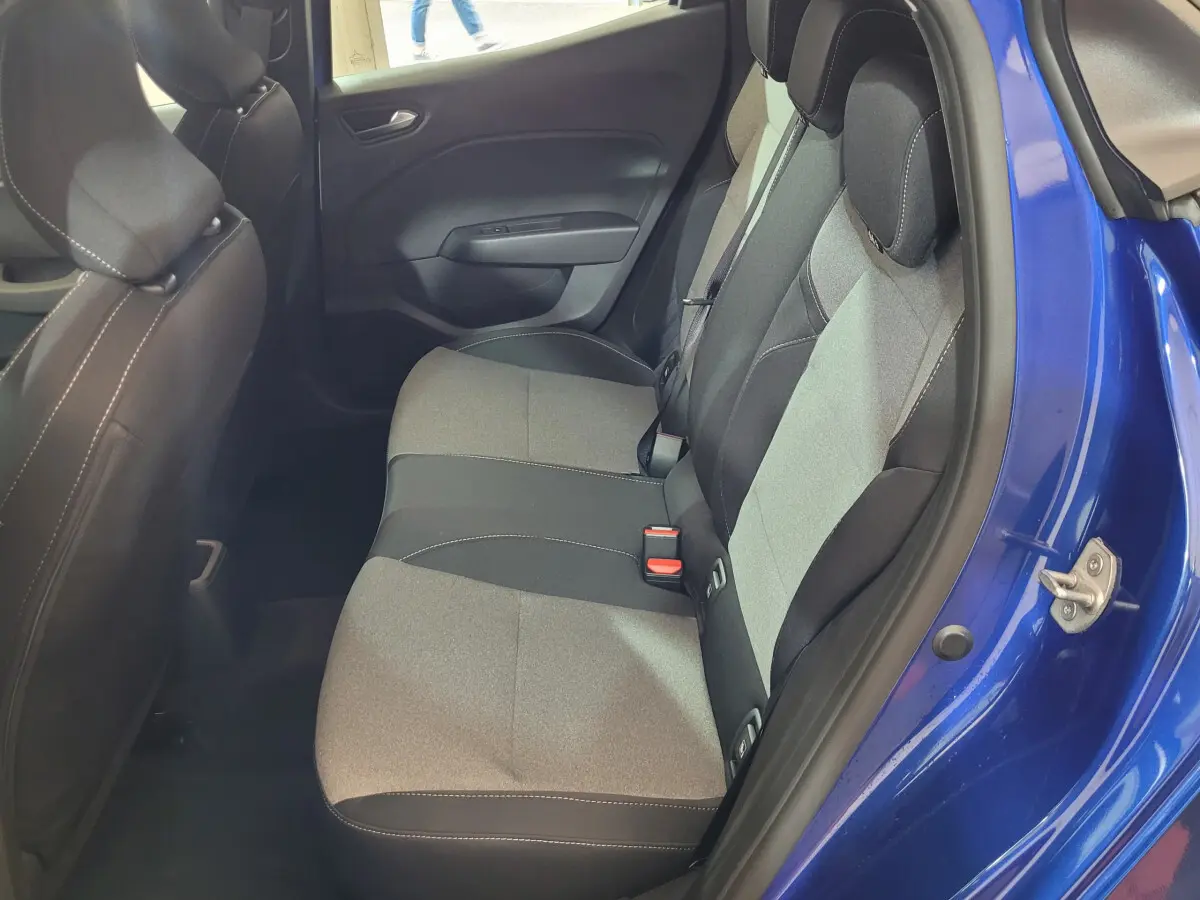 Vue intérieure côté droit sur la banquette arrière grise et noire d'une Renault Clio bleu 2025 avec porte ouverte.