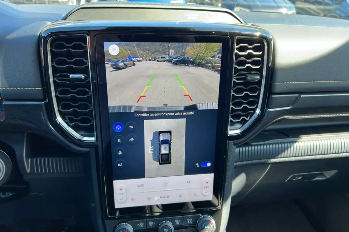 Vue rapprochée de l'écran central tactile du Ford Ranger 2025 gris carbone montrant la caméra de recul et les commandes climatisation.