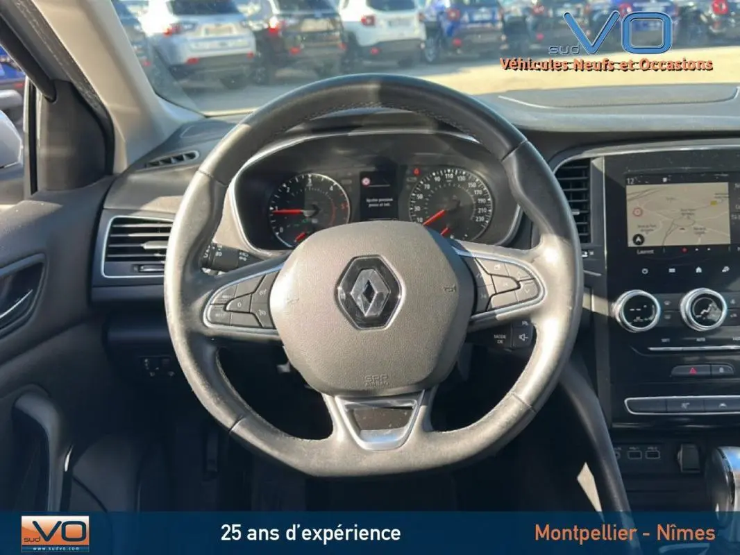 Vue intérieure centrée sur le volant Renault d'une Mégane IV Berline, tableau de bord et écran tactile visibles.