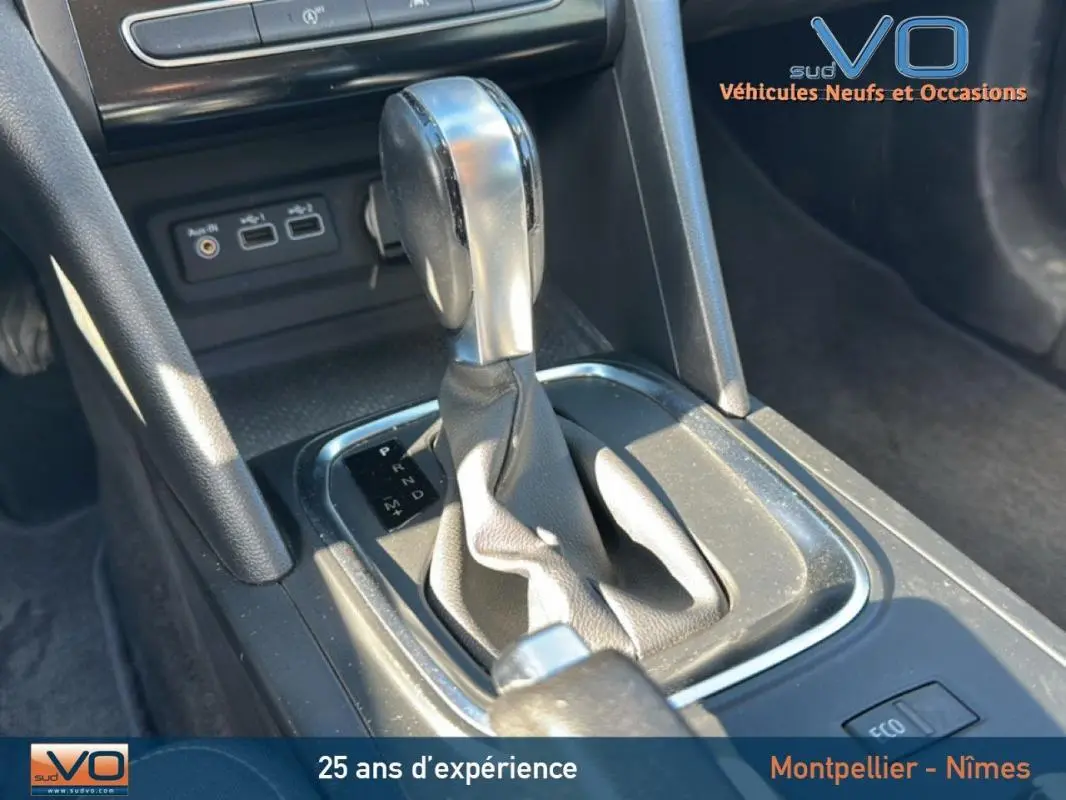Gros plan sur la console centrale de la Renault Mégane IV gris clair, avec levier de boîte automatique et commandes USB visibles.
