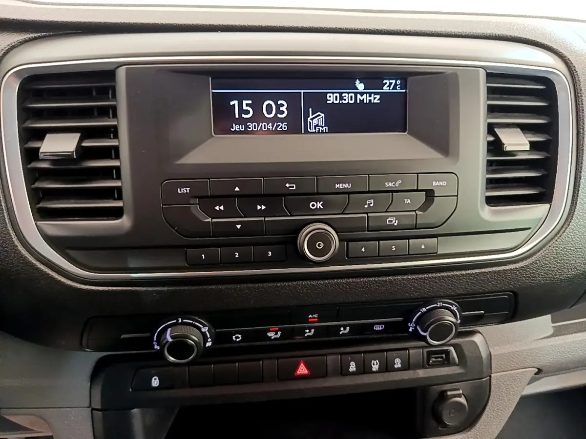 Vue rapprochée du tableau de bord noir du Peugeot Traveller 2018 avec écran central et commandes de climatisation.