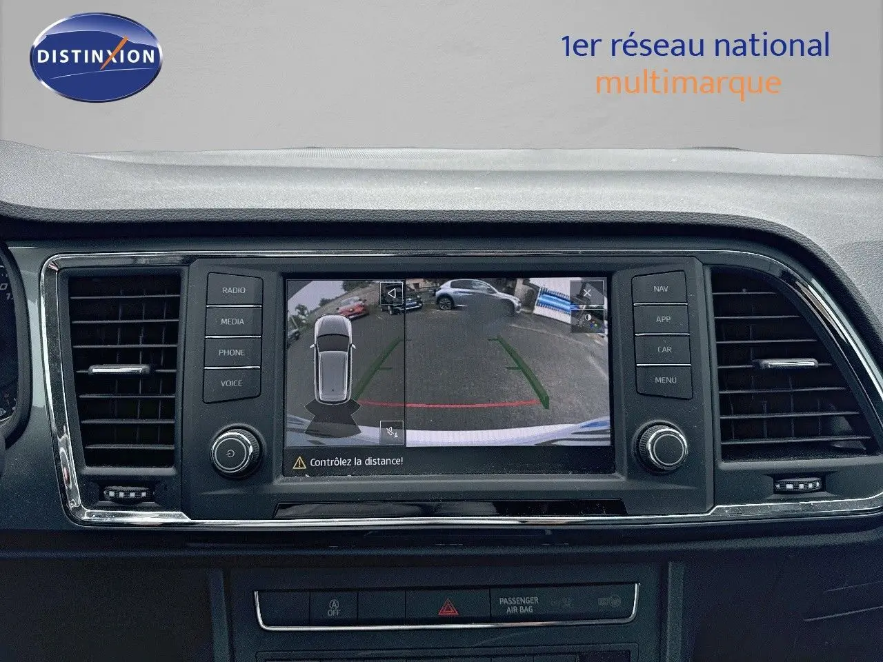 Écran central du SEAT Ateca blanc montrant la caméra de recul avec guidage de trajectoire en ville.