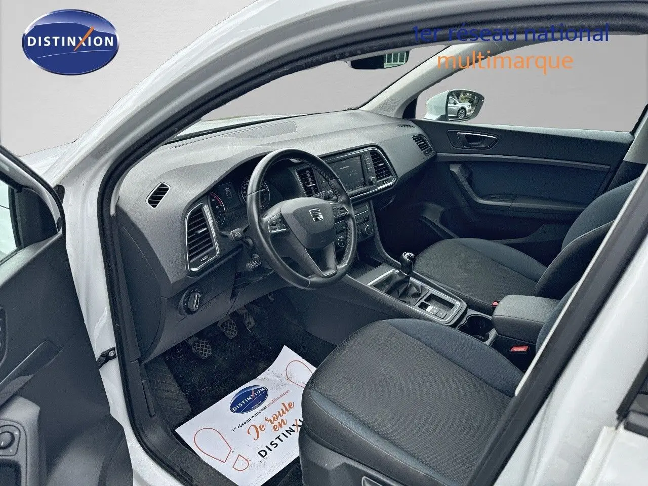 Vue intérieure côté conducteur du SEAT Ateca blanc Nevada 2018, montrant tableau de bord et sièges noirs.