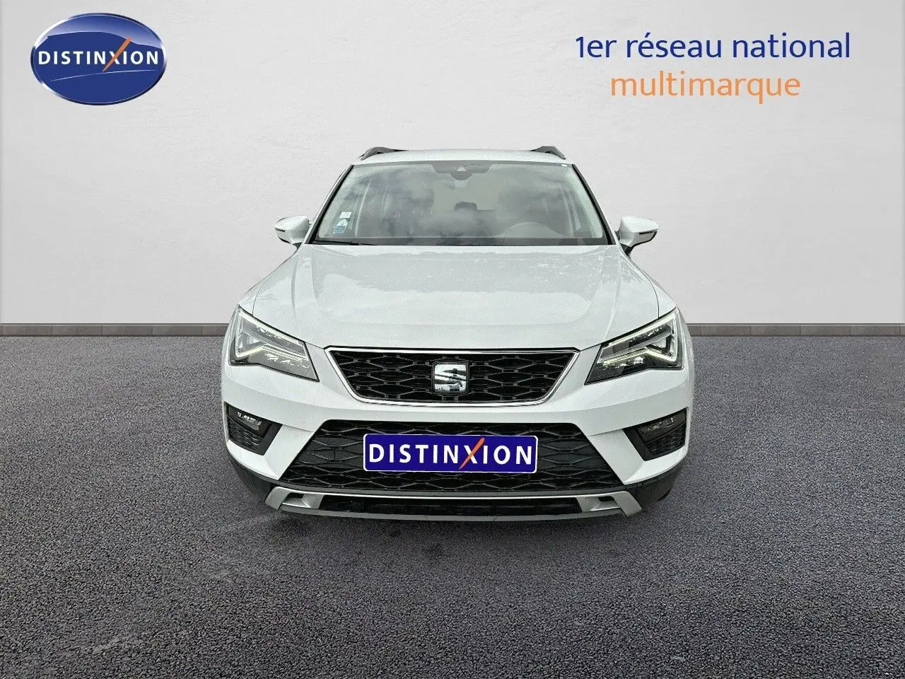 Vue frontale d'un SEAT Ateca blanc Nevada 2018 avec calandre noire et phares LED allumés sur fond neutre.