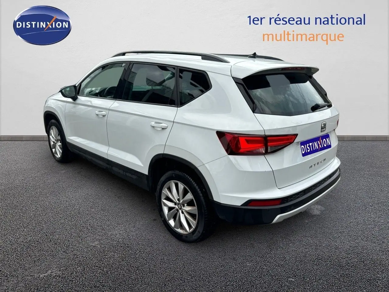 SEAT Ateca blanc Nevada en vue 3/4 arrière côté gauche, avec feux arrière LED et jantes alliage visibles.