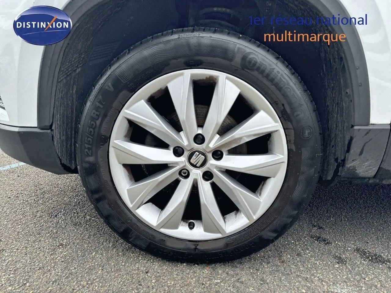 Gros plan sur la roue avant gauche du SEAT Ateca blanc Nevada, mettant en valeur la jante en alliage au design moderne.