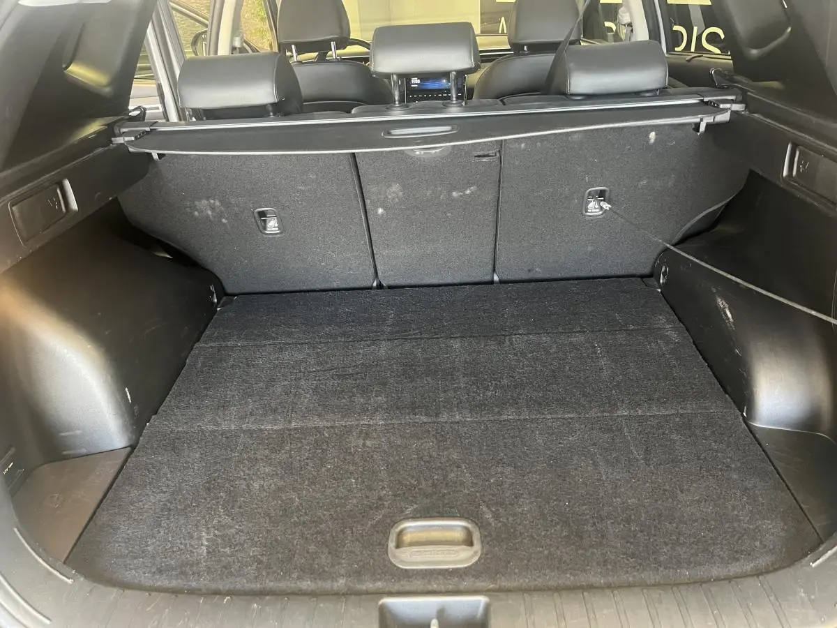 Coffre ouvert du Hyundai Tucson gris 2023, vue intérieure arrière montrant la plage arrière et les sièges rabattus.