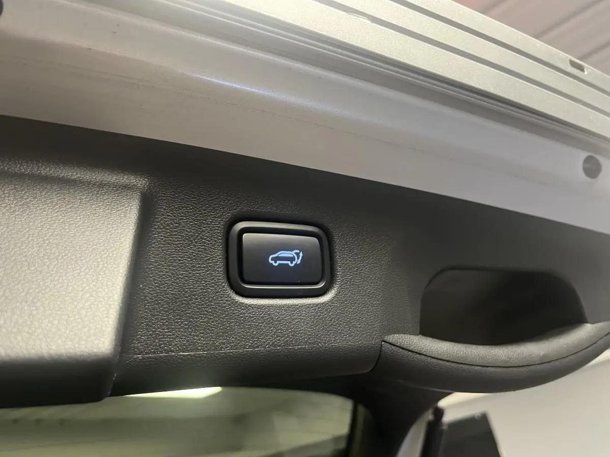 Bouton d'ouverture électrique du hayon sur le bord intérieur du coffre du Hyundai Tucson gris 2023.