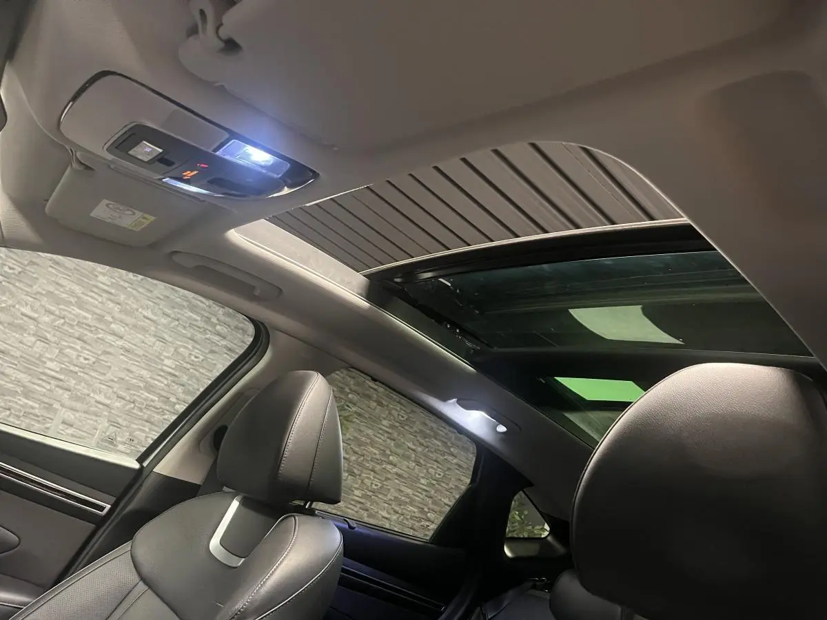 Intérieur du Hyundai Tucson 2023 vu côté gauche, avec toit ouvrant panoramique et sièges cuir noirs.