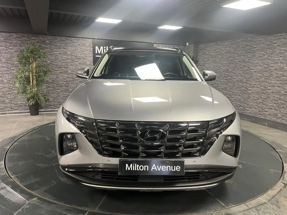 Vue avant d'un Hyundai Tucson gris métallisé 2023 avec calandre noire brillante et feux LED intégrés.