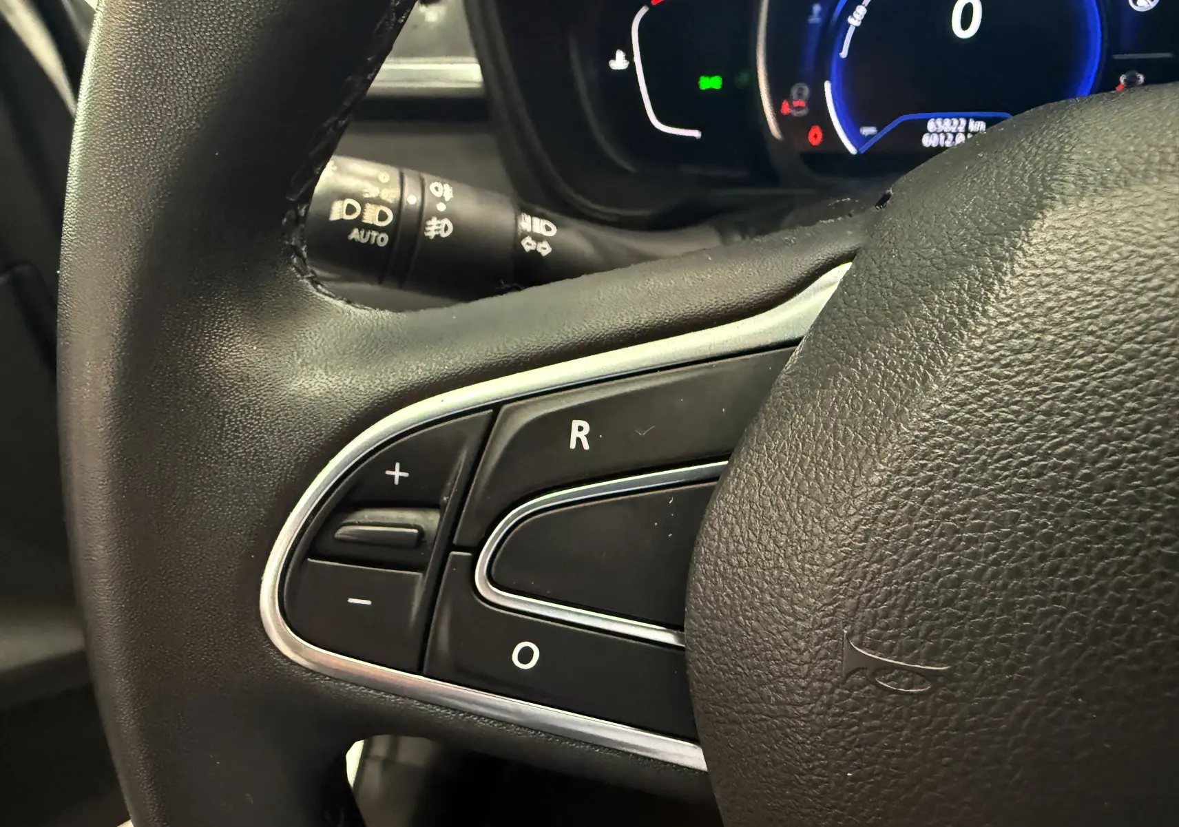Gros plan sur les commandes au volant côté gauche du Renault Kadjar 2020, tableau de bord numérique en arrière-plan.