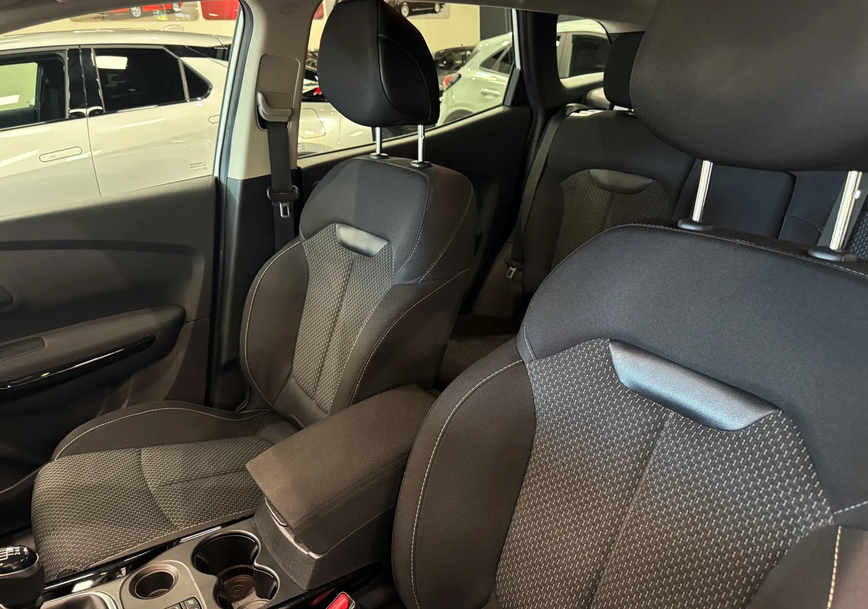 Vue intérieure du Renault Kadjar 2020 montrant les sièges avant en tissu noir et la console centrale avec accoudoir.