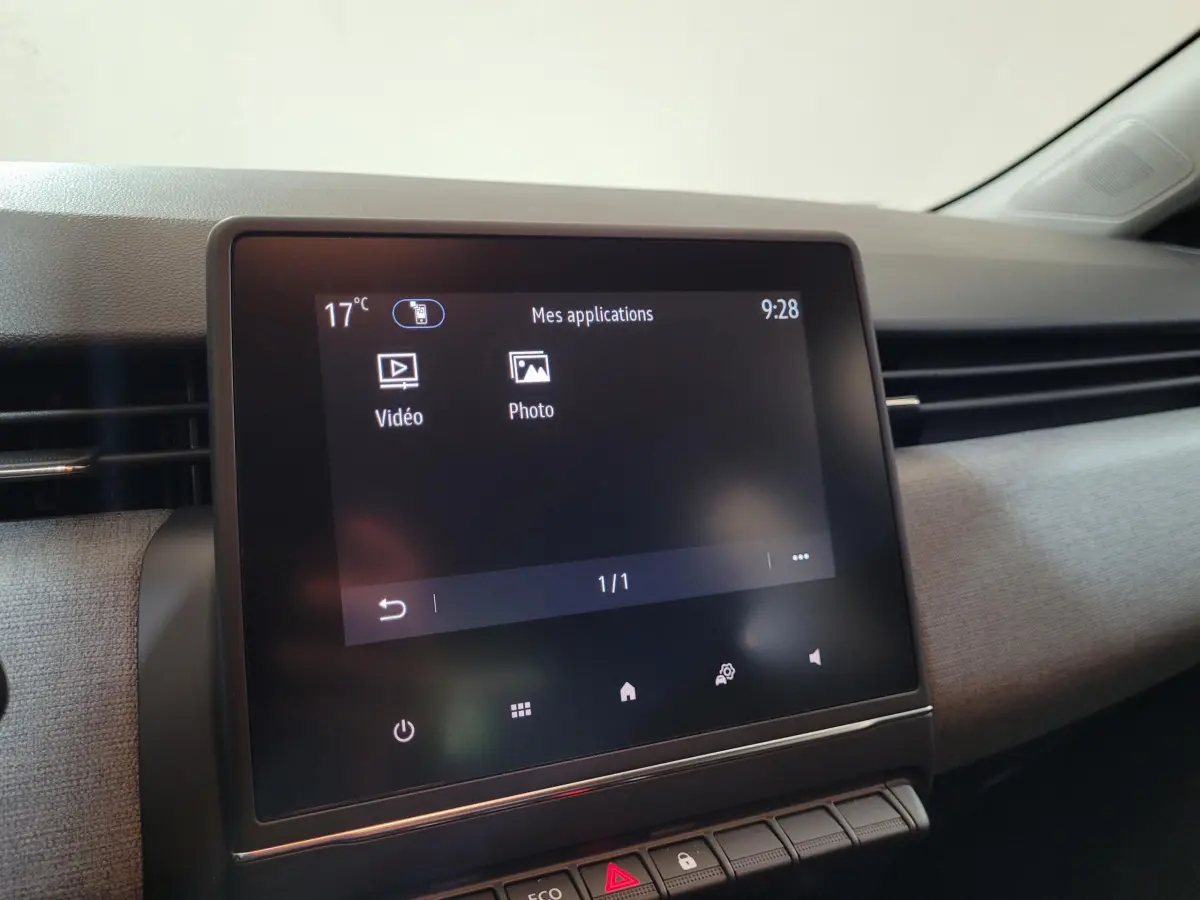 Écran tactile central allumé montrant les applications vidéo et photo dans l’habitacle gris clair d’une Renault Clio 2025.