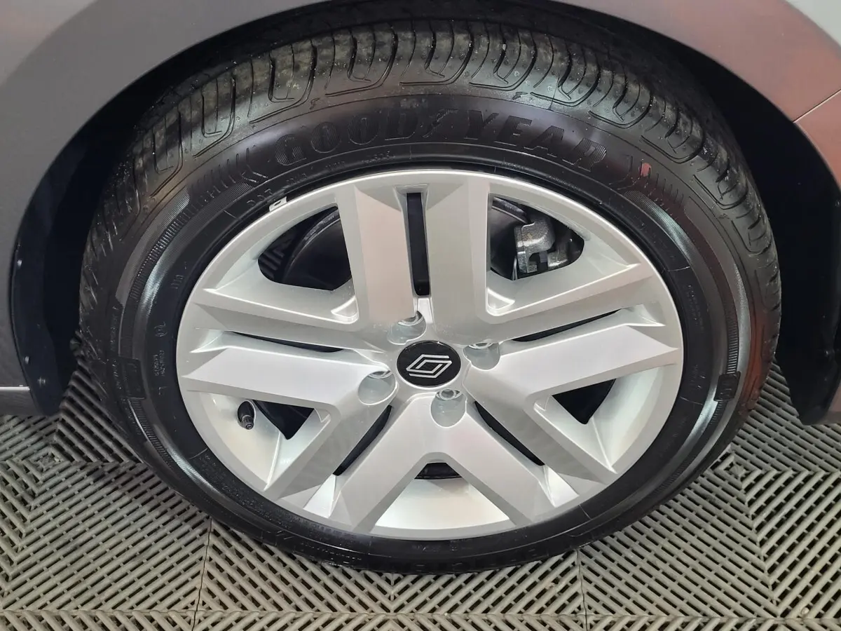 Gros plan sur la roue avant droite d'une Renault Clio gris foncé, mettant en valeur le pneu et l'aile du véhicule.