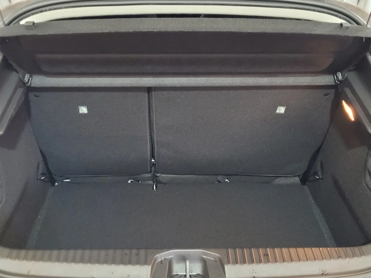 Coffre ouvert vu de l'arrière d'une Renault Clio gris foncé, montrant l'espace de chargement et la banquette arrière rabattable.