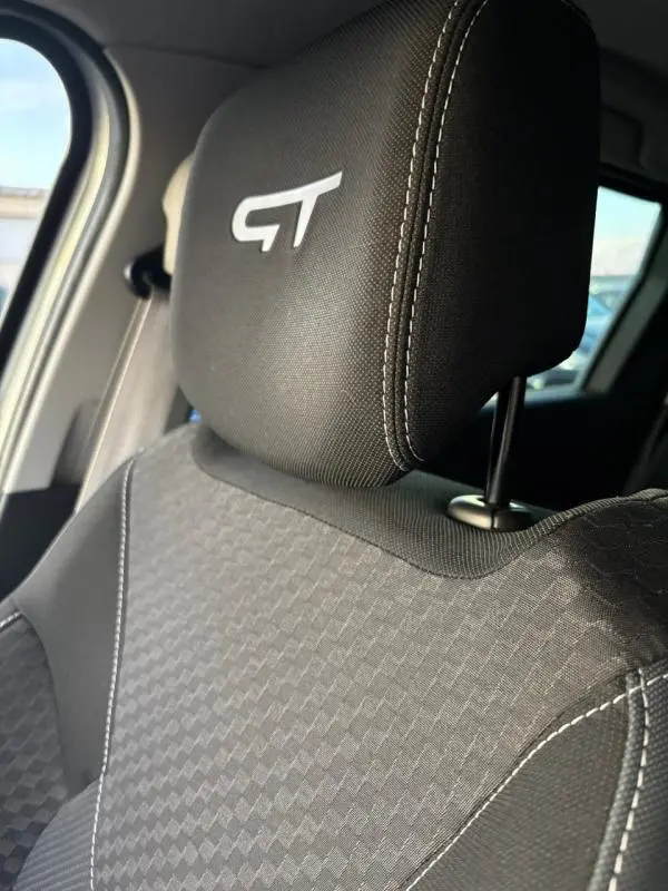 Gros plan sur l'appui-tête avant gauche brodé GT et le tissu gris à motifs du siège Renault Clio IV Estate TCe 120 GT EDC.