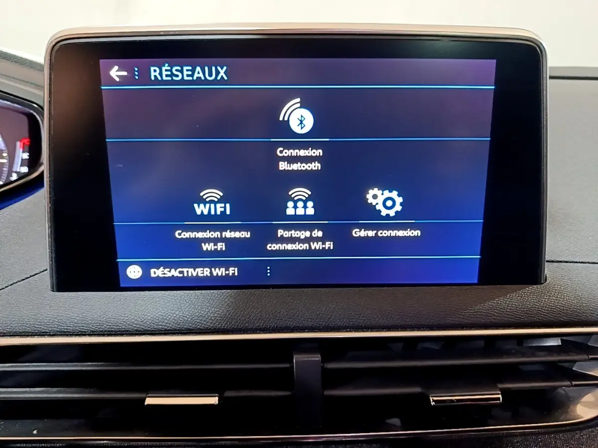 Écran tactile central affichant les options réseau Wi-Fi et Bluetooth dans le tableau de bord d’un Peugeot 3008 gris foncé.