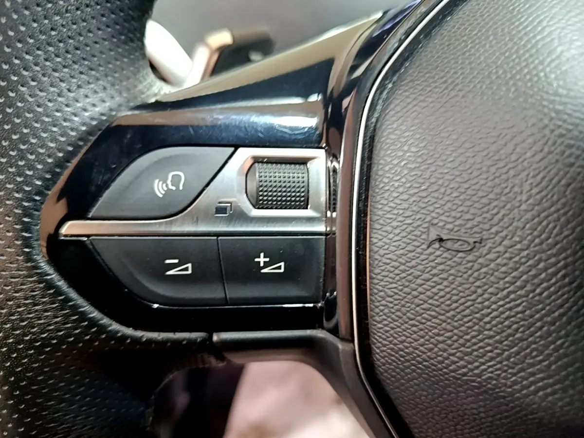 Gros plan sur les commandes multifonctions en plastique noir et chrome du volant cuir du Peugeot 3008 gris foncé.