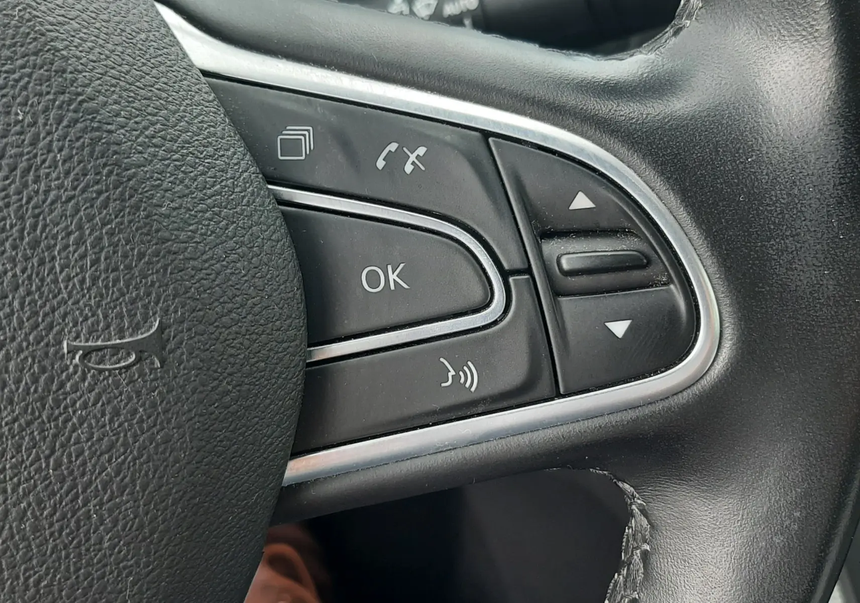 Gros plan sur les commandes multifonctions noires du volant cuir du Renault Scénic IV blanc nacré, version 2021.