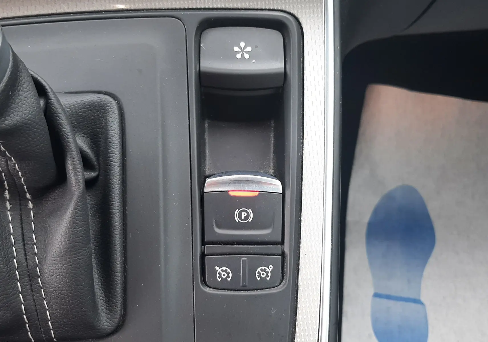 Vue rapprochée de la console centrale noire avec levier de vitesse et boutons de frein à main et régulateur sur Renault Scenic IV blanc nacré.