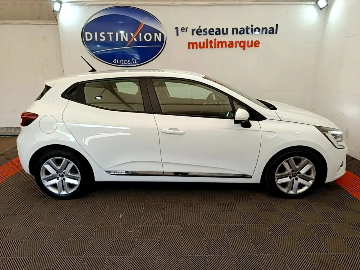 Vue de profil droit d'une Renault Clio Business Blue dCi 85 blanche, avec jantes alliage et feux LED visibles.