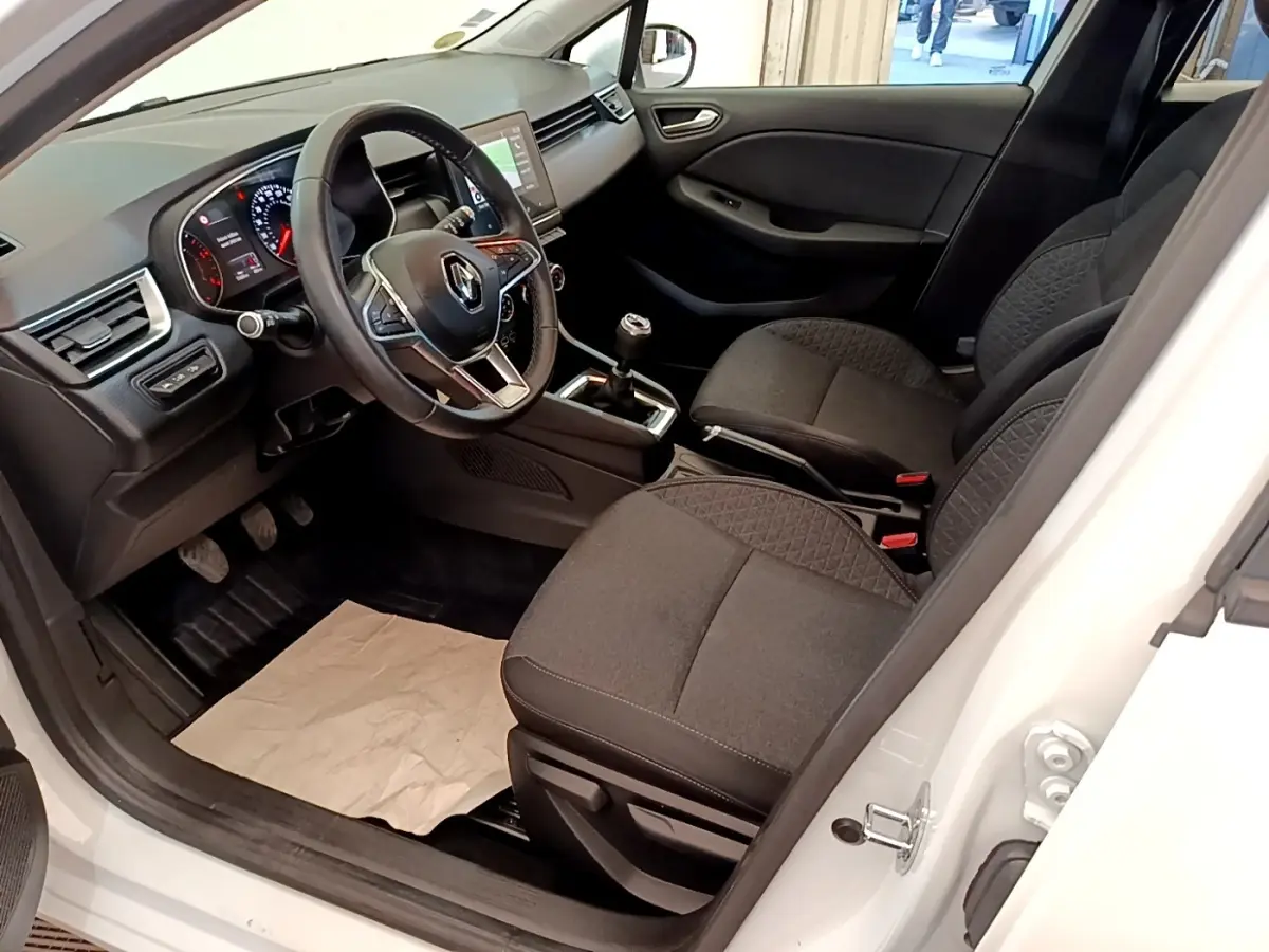 Intérieur de Renault Clio Business Blue dCi 85 blanc, vue côté conducteur, volant multifonction et sièges tissu noirs.