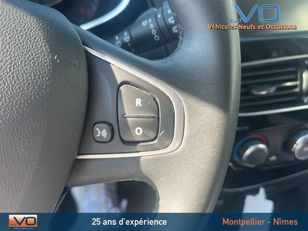 Gros plan sur le volant cuir de la Renault Clio IV Estate Business blanc, avec commandes audio et tableau de bord en arrière-plan.