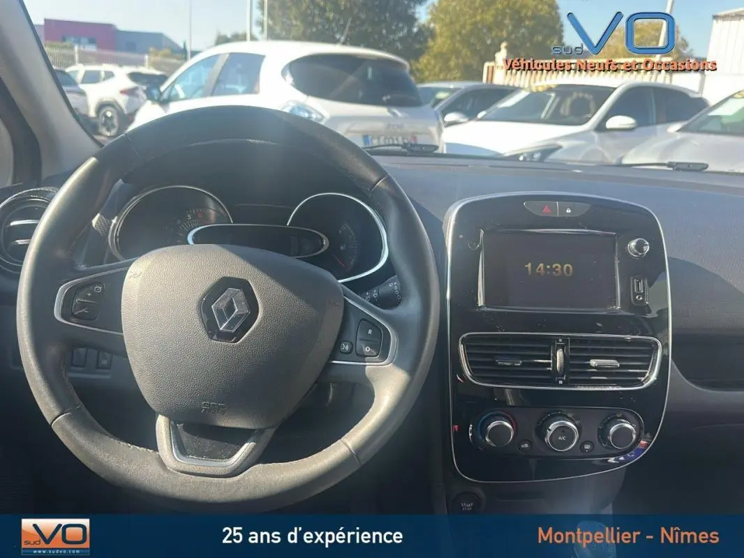 Vue intérieure du tableau de bord et volant cuir Renault Clio IV Estate Business blanc, avec écran central et commandes de climatisation.