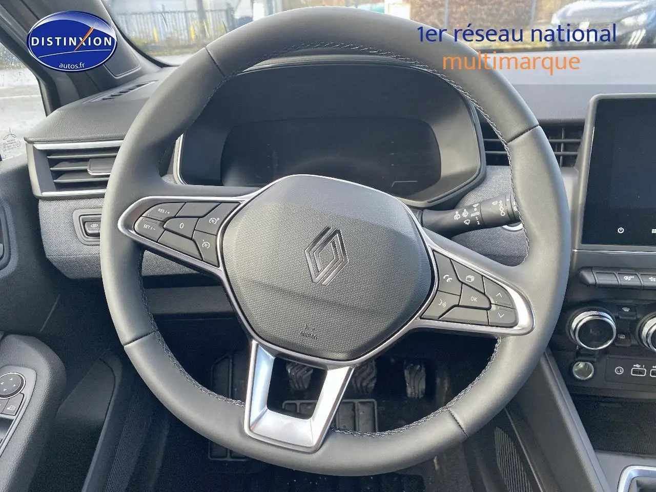 Vue intérieure centrée sur le volant multifonction noir de la Renault Clio V gris rafale avec tableau de bord et écran tactile.
