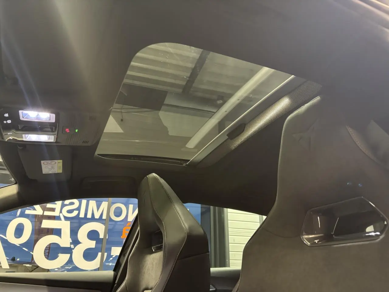 Vue intérieure du toit ouvrant panoramique et sièges baquets suédine noirs avec surpiqûres cuivrées de la CUPRA Leon 2026.