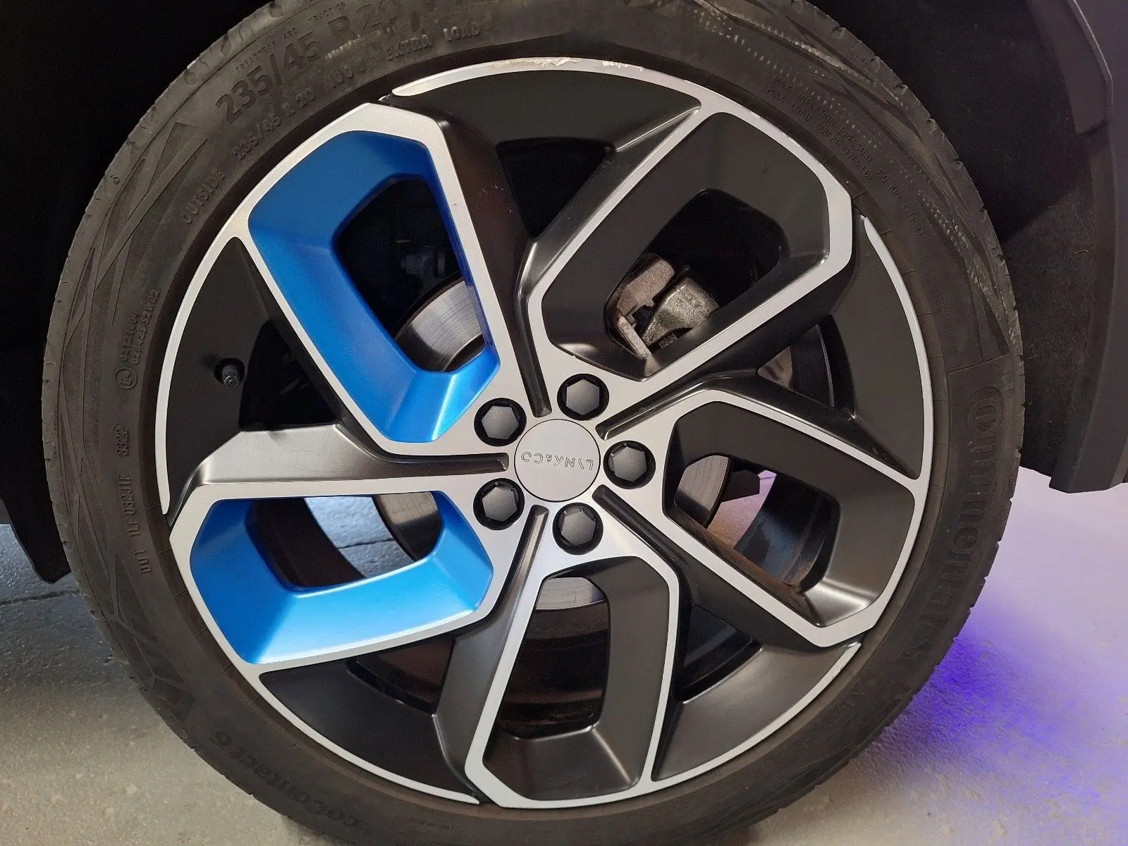 Gros plan sur la jante avant droite du Lynk & Co 01 PHEV 2022, avec inserts bleus et peinture noire métallisée.