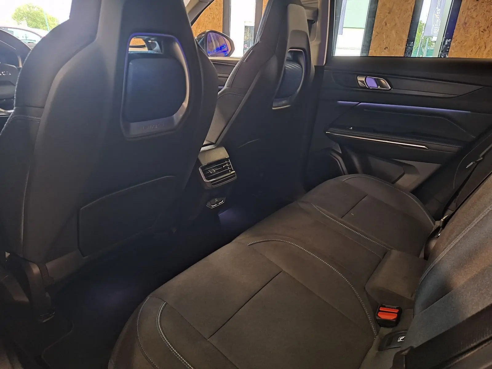 Vue intérieure arrière côté droit du Lynk & Co 01 PHEV 2022 avec sièges noirs et éclairage d'ambiance violet.