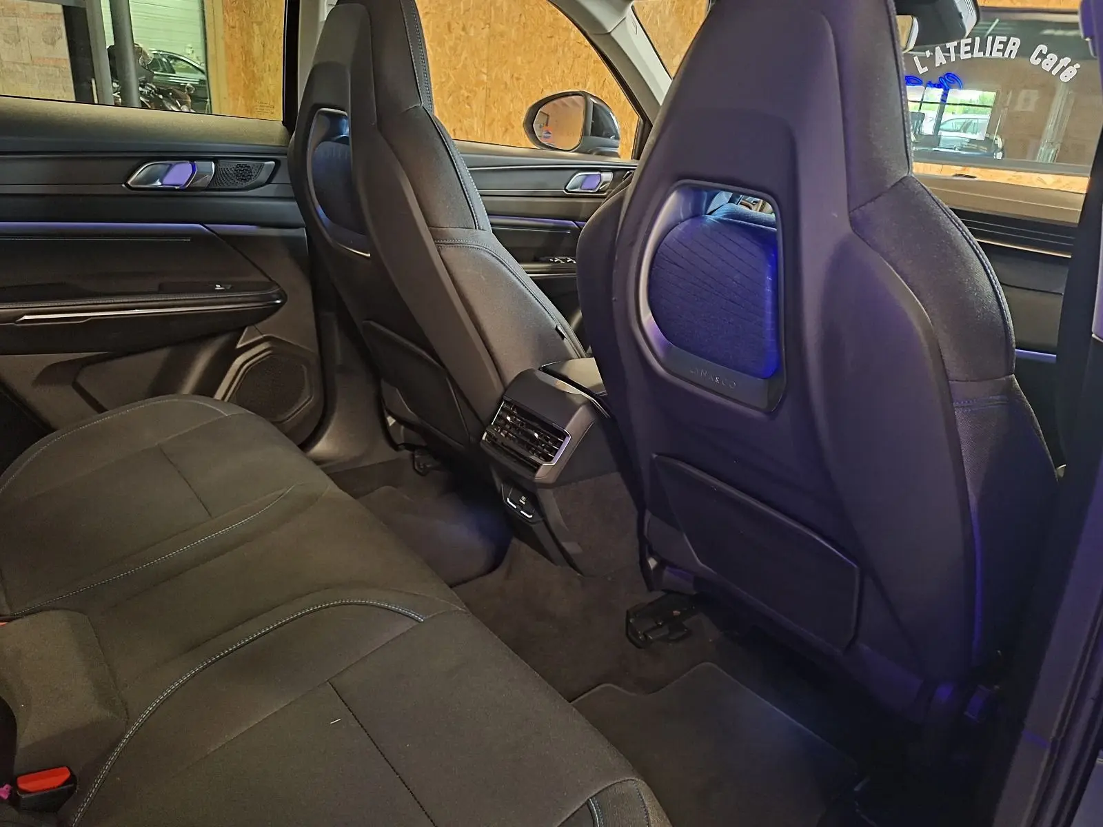 Vue intérieure arrière du Lynk & Co 01 noir, montrant les sièges avant avec éclairage d'ambiance bleu et banquette arrière.