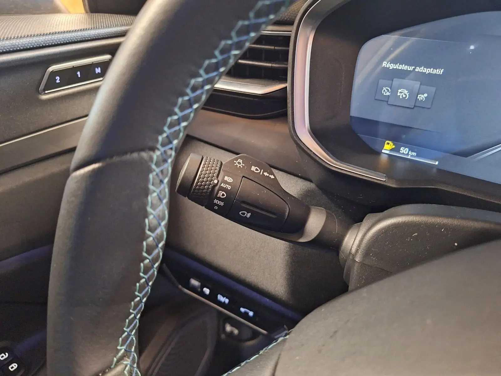 Vue rapprochée du volant et du combiné d'instruments du Lynk & Co 01 PHEV 2022, avec surpiqûres bleues et affichage du régulateur adaptatif.