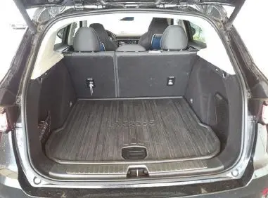 Vue de profil côté gauche du SUV Lynk & Co 01 PHEV noir avec jantes alliage à touches bleues dans un garage.