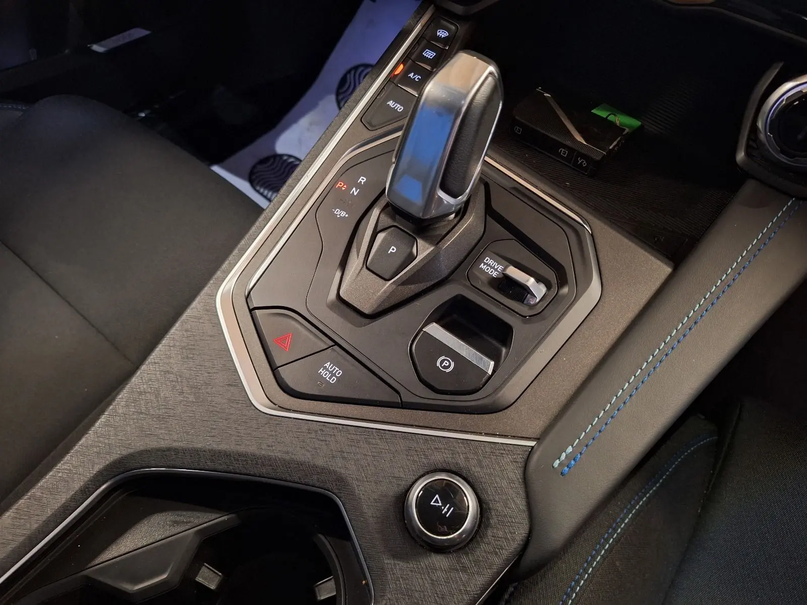 Gros plan sur la console centrale du Lynk & Co 01 PHEV 261 DCTH7 noire, avec levier de vitesse et surpiqûres bleues.