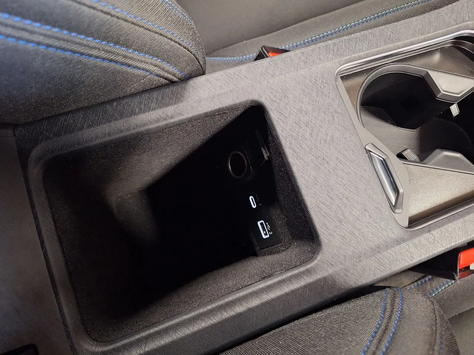 Gros plan sur la console centrale noire du Lynk & Co 01 PHEV 2022 avec ports USB et porte-gobelets.