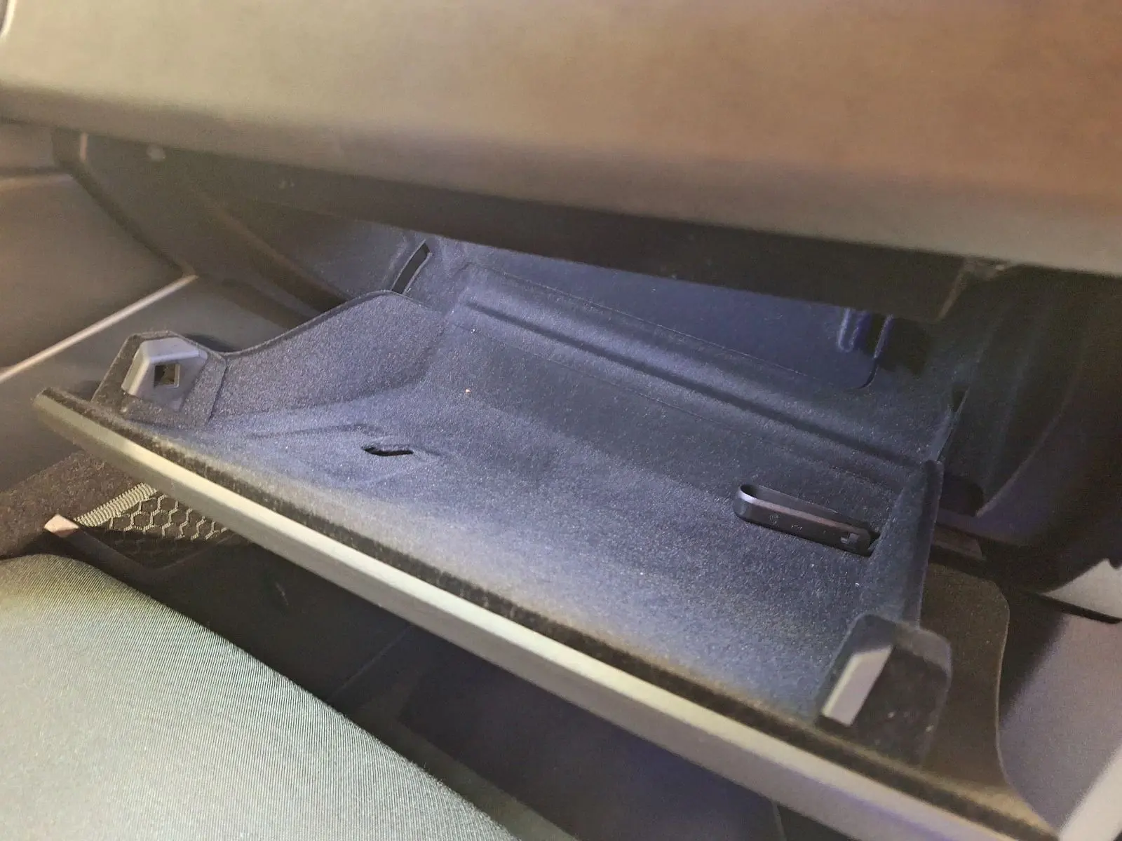 Gros plan sur la boîte à gants noire ouverte du Lynk & Co 01 PHEV 261 DCTH7, intérieur tissu sombre.