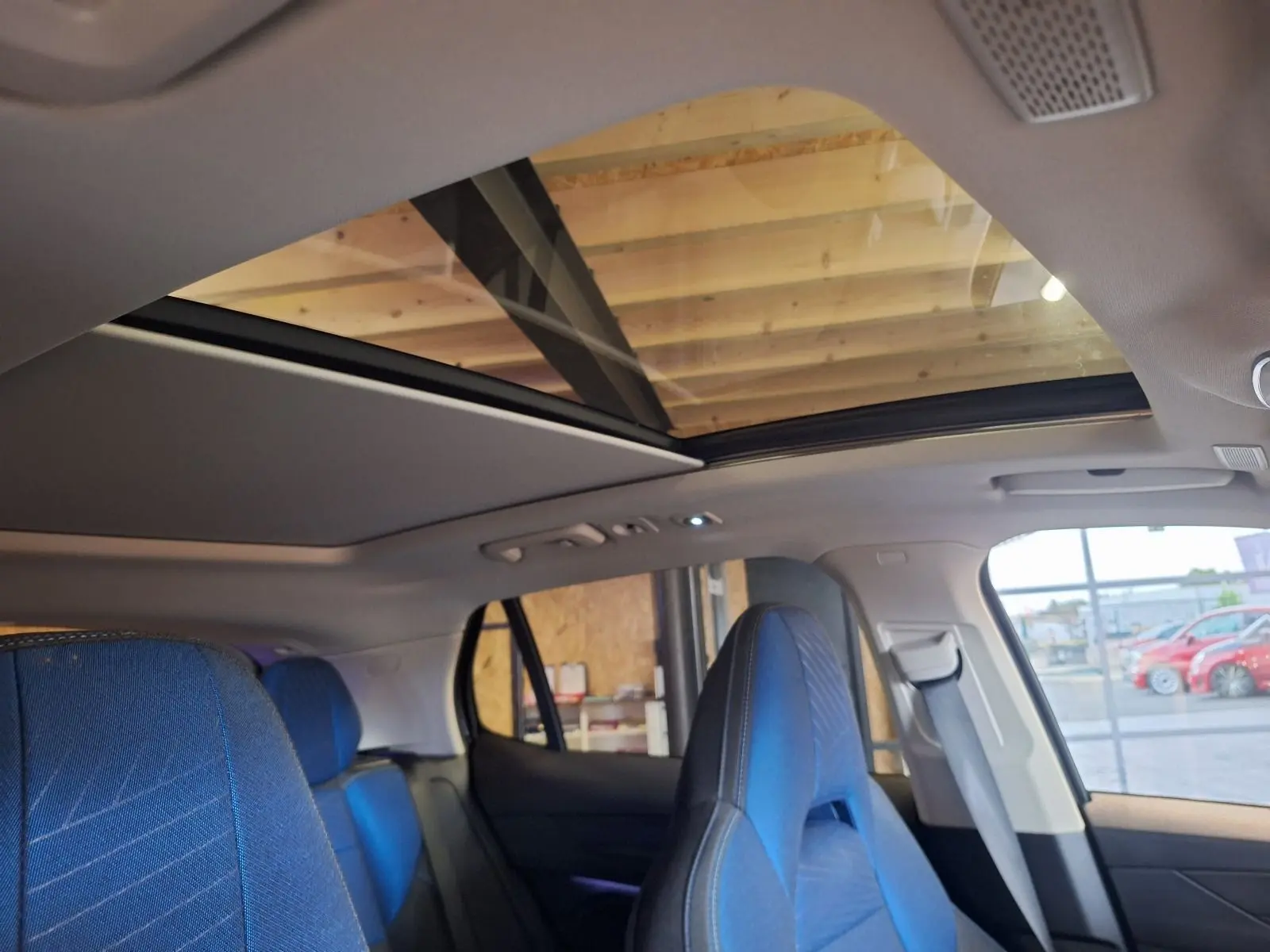 Vue intérieure du toit panoramique électrique et des sièges avant bleus du LYNK & CO 01 noir PHEV 2022.