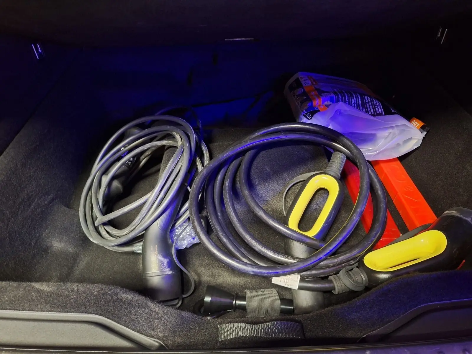 Coffre ouvert d'un Lynk & Co 01 noir 2022, montrant câbles de recharge hybrides et accessoires rangés.