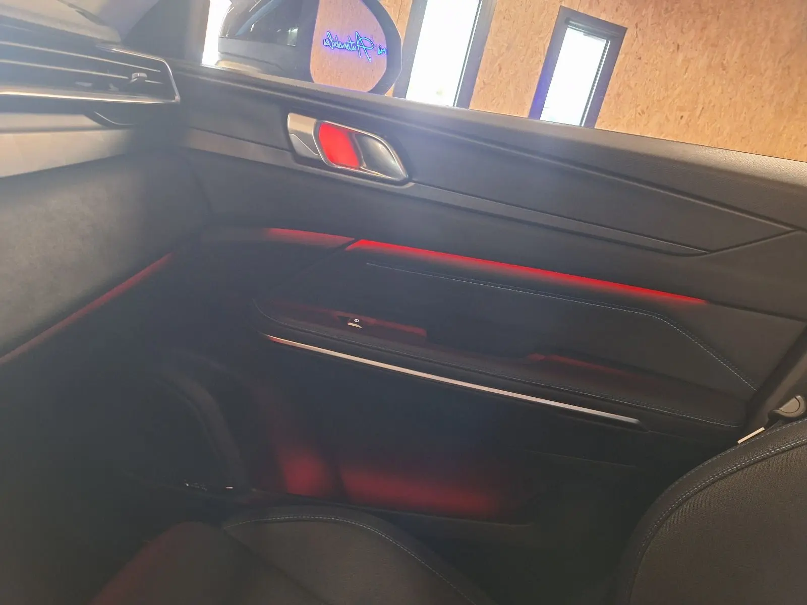 Détail de la porte côté droit du Lynk & Co 01 PHEV 2022 avec éclairage d’ambiance rouge et garnitures noires.