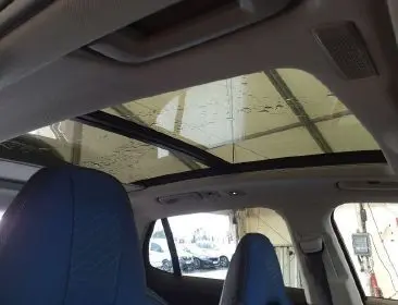 Vue 3/4 arrière côté gauche du LYNK & CO 01 noir avec toit panoramique ouvert dans un atelier.