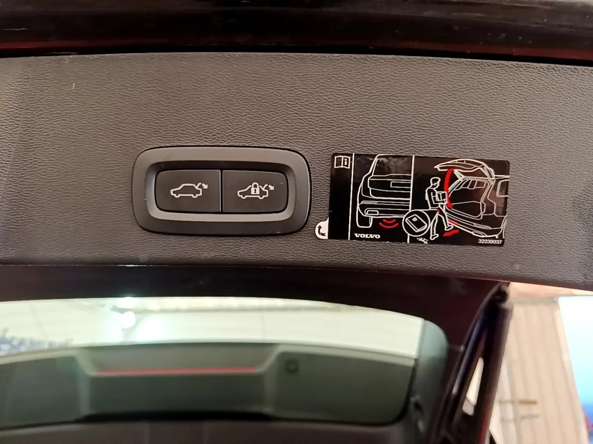 Gros plan sur les boutons d'ouverture et de verrouillage électrique du coffre du Volvo XC40 noir, vue intérieure du hayon ouvert.