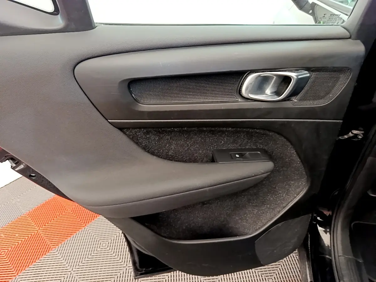 Gros plan sur la porte intérieure côté gauche noire du Volvo XC40 T2 Momentum avec poignée métal et commande de vitre.
