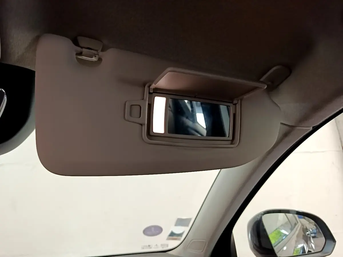 Miroir de courtoisie ouvert sur pare-soleil beige côté conducteur dans un Volvo XC40 noir, vue intérieure avant gauche.