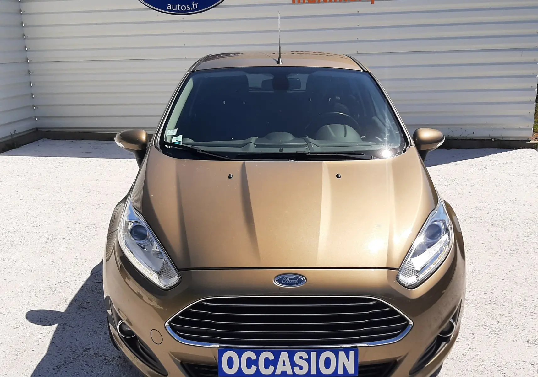 Vue avant d'une Ford Fiesta marron métal 2013 avec calandre chromée et plaque "OCCASION" visible.